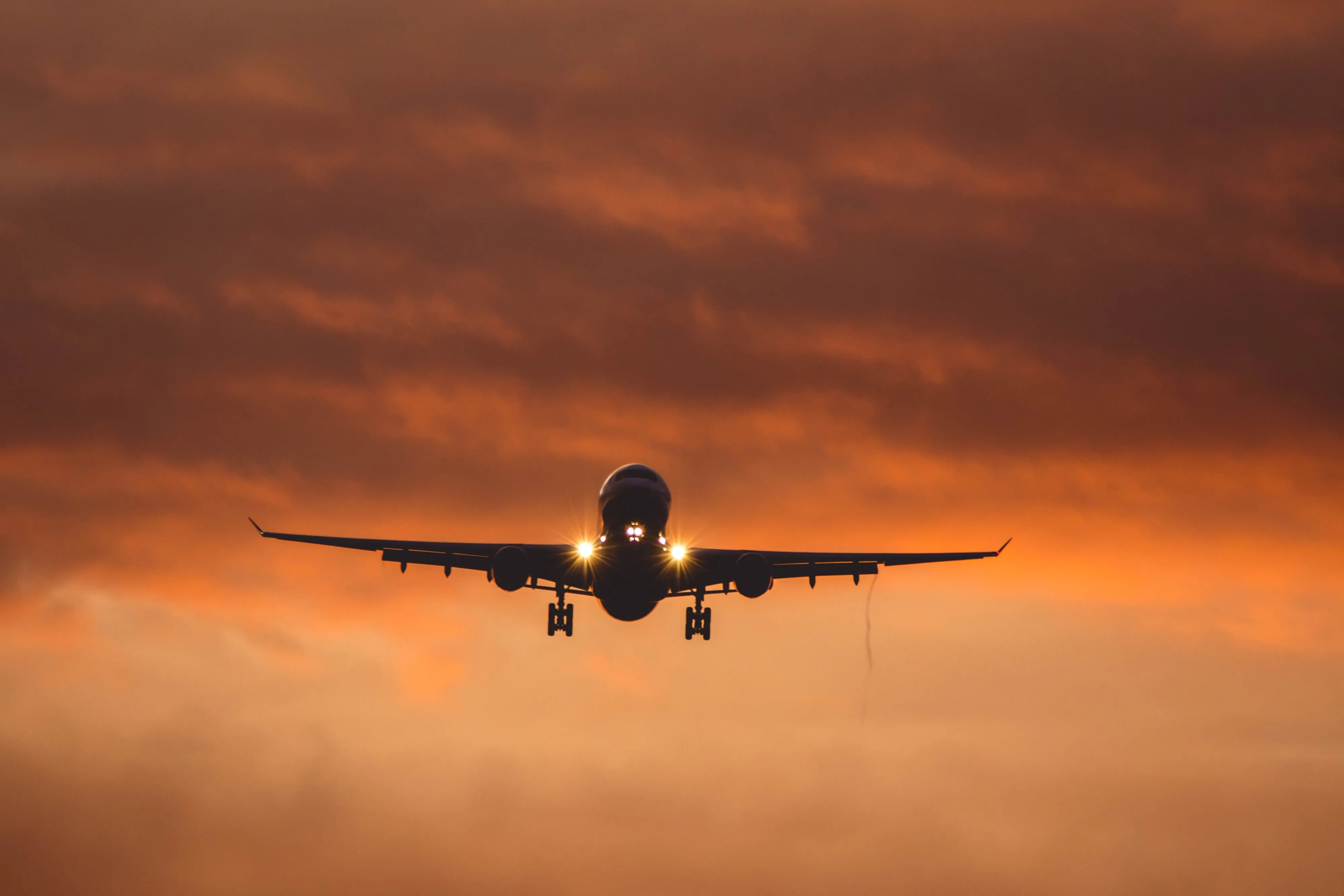 An airliner on final approach against a sunset sky