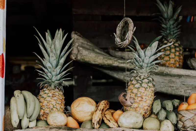 Pineapples and bananas piled at a tropical fruit stall in a Colombian market