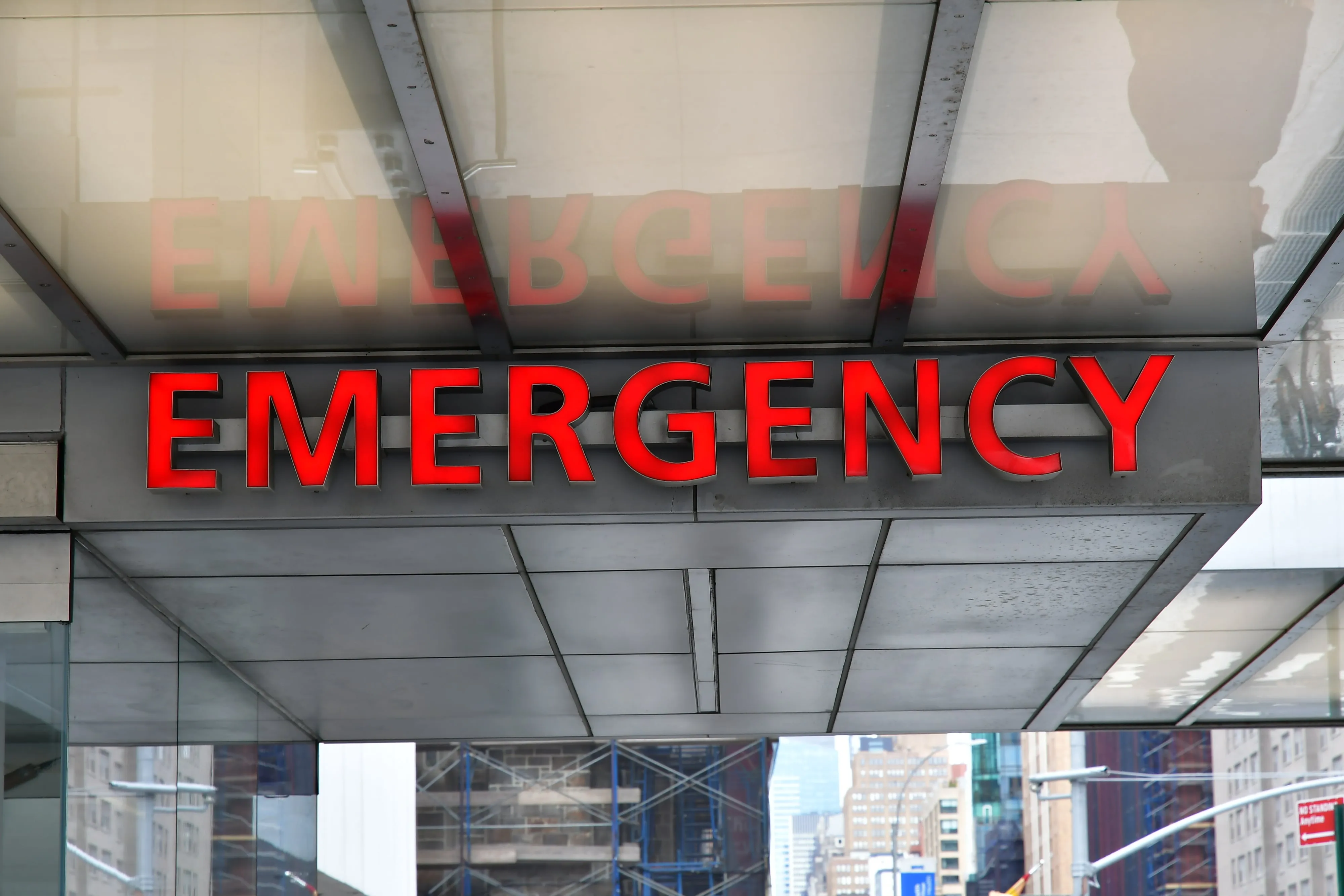 A red illuminated EMERGENCY sign above the entrance to a hospital